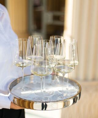 server with glasses of white wine on tray
